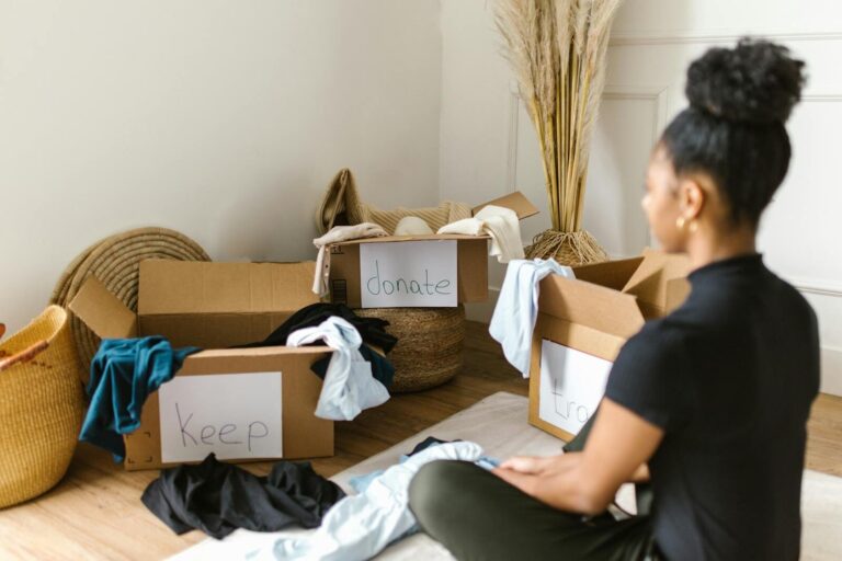 A woman organising clothes into labeled boxes for donation and keeping.